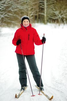 Happy girl posing on skis in the winter woods.