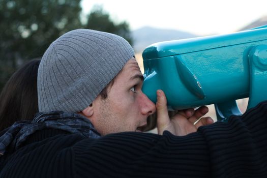 Boy looking through a turquoise telescope