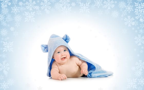 Small smiling baby with a towel on snowy background