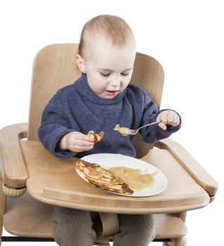 young child eating in high chair isolated in white backgound