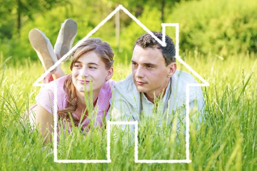 Young couple lying on grass dreaming to a house