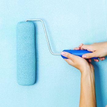 woman paints the wall roller