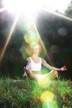 yoga woman on green grass lotus pose in sunrise light