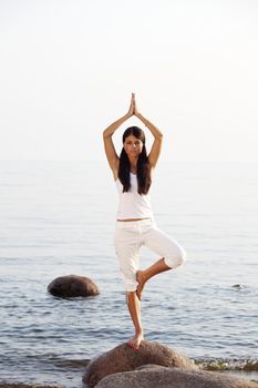 Young woman practicing yoga  near the ocean