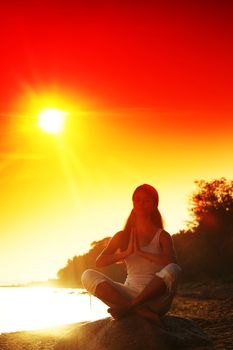 Young woman practicing yoga  near the ocean