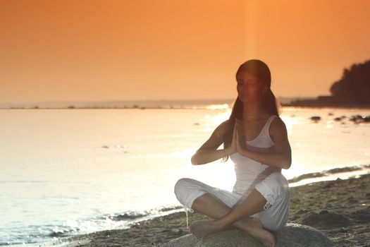 Young woman practicing yoga  near the ocean