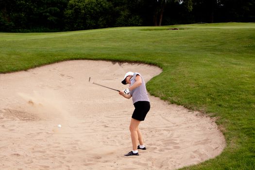 woman is playing golf on course  in summer in a golf-club