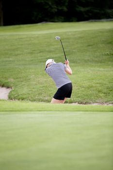 woman is playing golf on course  in summer in a golf-club