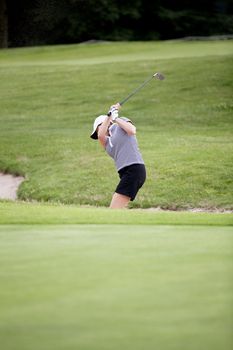 woman is playing golf on course  in summer in a golf-club