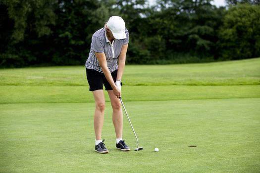 woman is playing golf on course  in summer in a golf-club