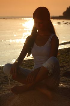 Young woman practicing yoga  near the ocean