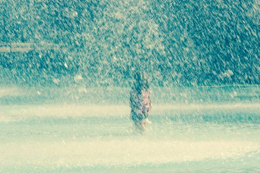 a girl in a splashing fountain in a city park