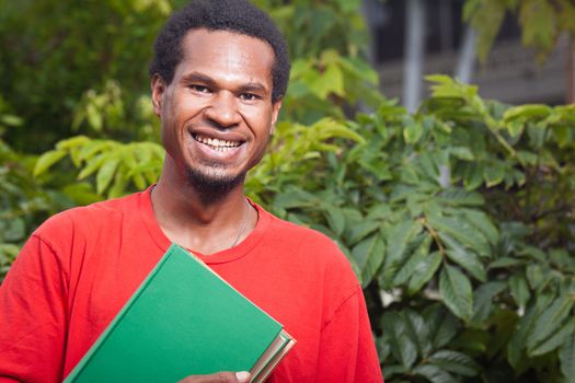 Portrait of a happy smiling young male student from south east asia carrying school books