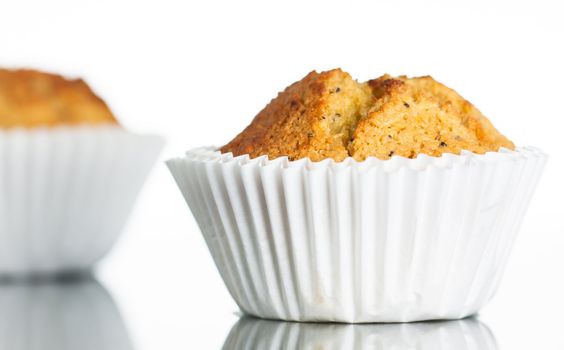 Close-up of a freshly home baked banana muffin on a reflective surface. Isolated on white.