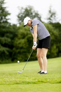 woman is playing golf on course  in summer in a golf-club