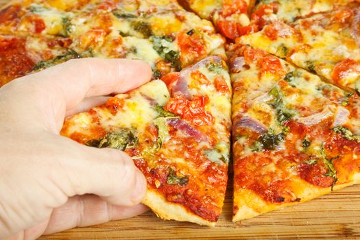 Close-up of a hand taking a slize of homemade pizza