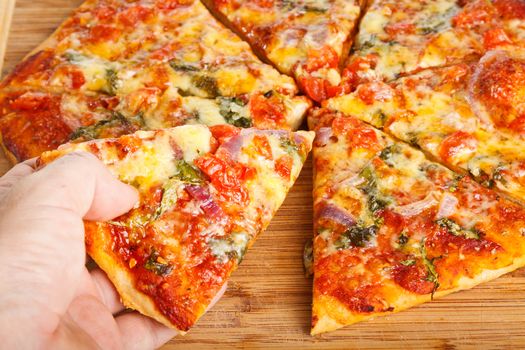 Close-up of a hand taking a slize of homemade pizza