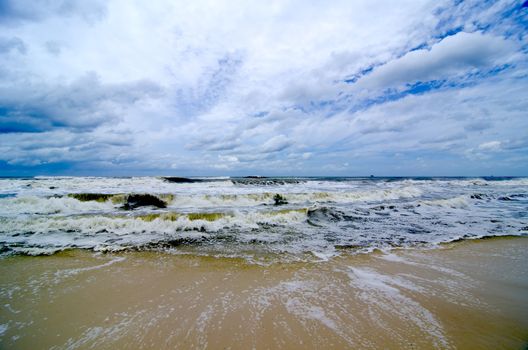 Tropical storm waves crashing on the coast with storm clouds above.