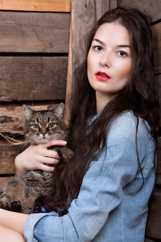 Portrait of a woman with a cat on the background of wooden walls.