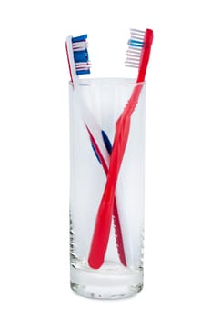Toothbrushes in glass beaker on white background.