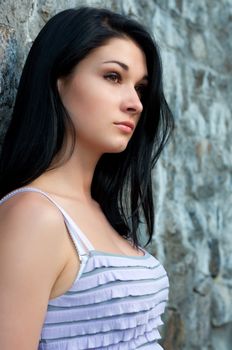 Sad young woman near stone wall close-up portrait.