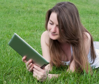 Woman lying on lawn with tablet.