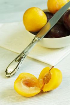 Cuted yellow plum and bowl with plums at the background