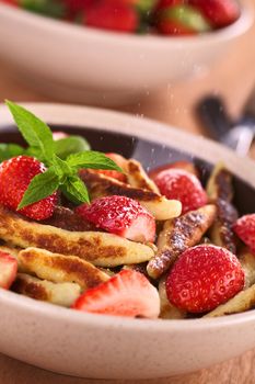 Schupfnudeln (Swabian potato noodles from Southern Germany) with fresh strawberries, cinnamon and sugar powder (Selective Focus, Focus on the front of the strawberry in the middle of the image and on the tip of the mint) 