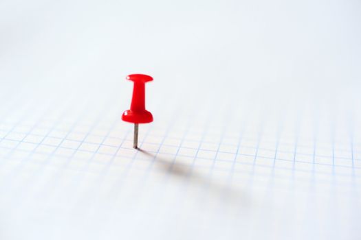 An image of red pin on squared paper