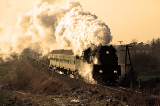 Vintage steam train passing through countryside, wintertime
