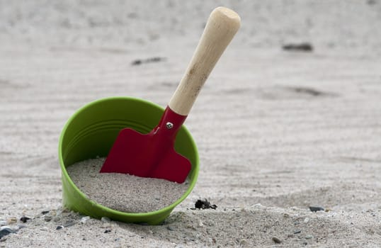 red and green shovel and bucket on the beach