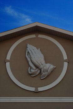 prayer hands against blue sky