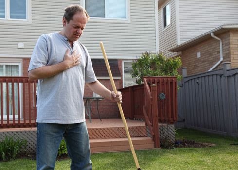 man having a heart attack chest pains while doing yard work
