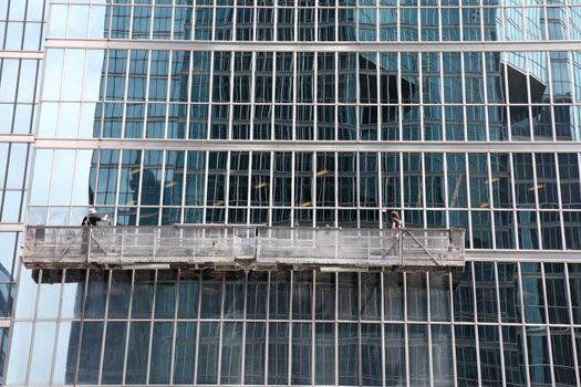 window washer cleaning windows on a modern highrise office tower building in the city