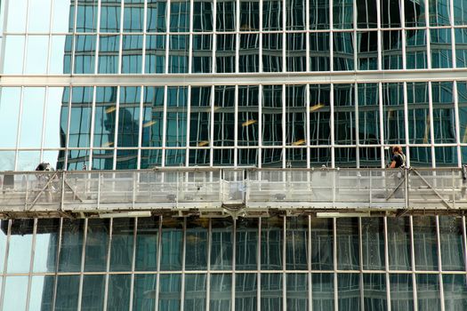 window washer cleaning windows on a modern highrise office tower building in the city