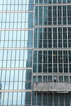 window washer cleaning windows on a modern highrise office tower building in the city