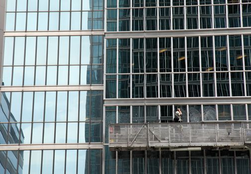 window washer cleaning windows on a modern highrise office tower building in the city