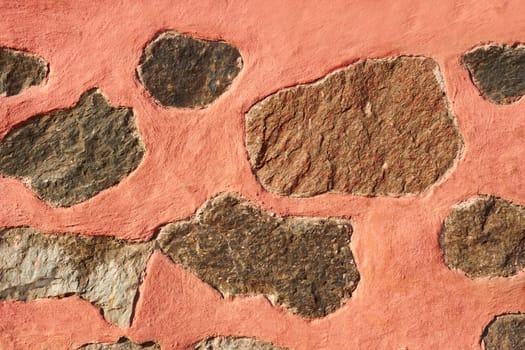 Granite stone boulders interspersed in concrete painted in reddish color