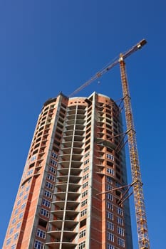 Building cranes on the construction of dwelling skyscraper. Serene sunny day