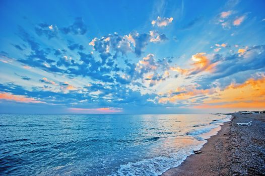 Sunset sky over the sea, sandy beach.