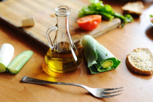 A bottle of olive oil and vegetables on the table