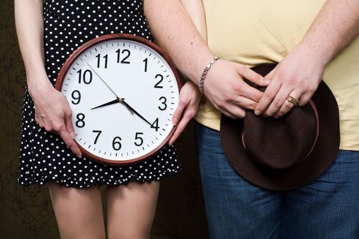 An image of man and woman with hat and clock