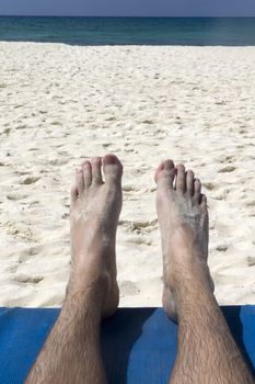 Two feet relaxing on a beach by the ocean