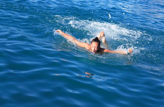 Beauty teenage girl swimming the butterfly stroke in a sea