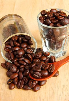 Coffee beans in glasses with spoon on wooden background