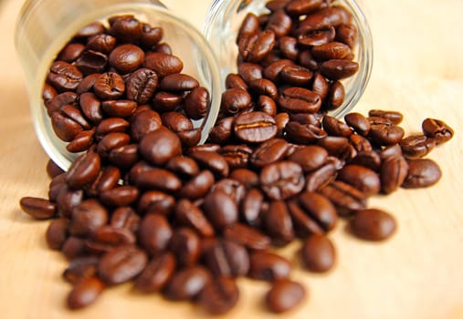 Coffee beans in glasses on wooden background