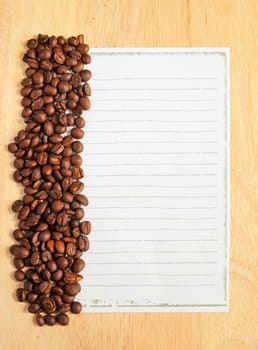Coffee beans with paper for notes on the wooden background