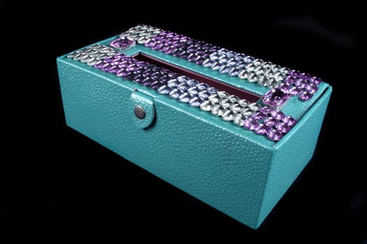 An ethnic napkin / tissue-paper box made of leather, cardboard studded with colorful decorative stones.