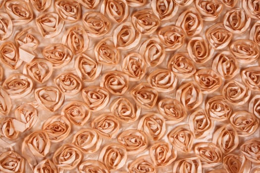 A background of an orange fabric with a pattern of roses. 