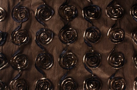 A background of a brown fabric with a beautiful swirling pattern.